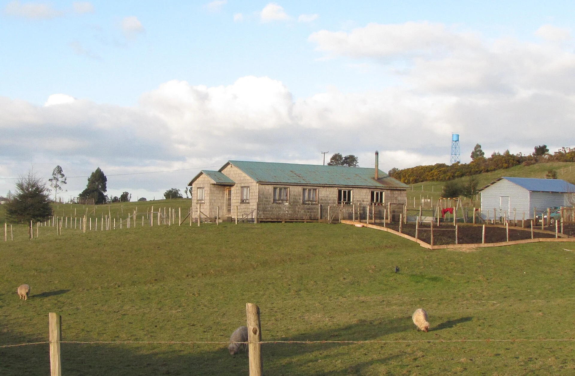 Casa de tejuelas y campo en Rauco Alto, Chiloé, fotografía referencial